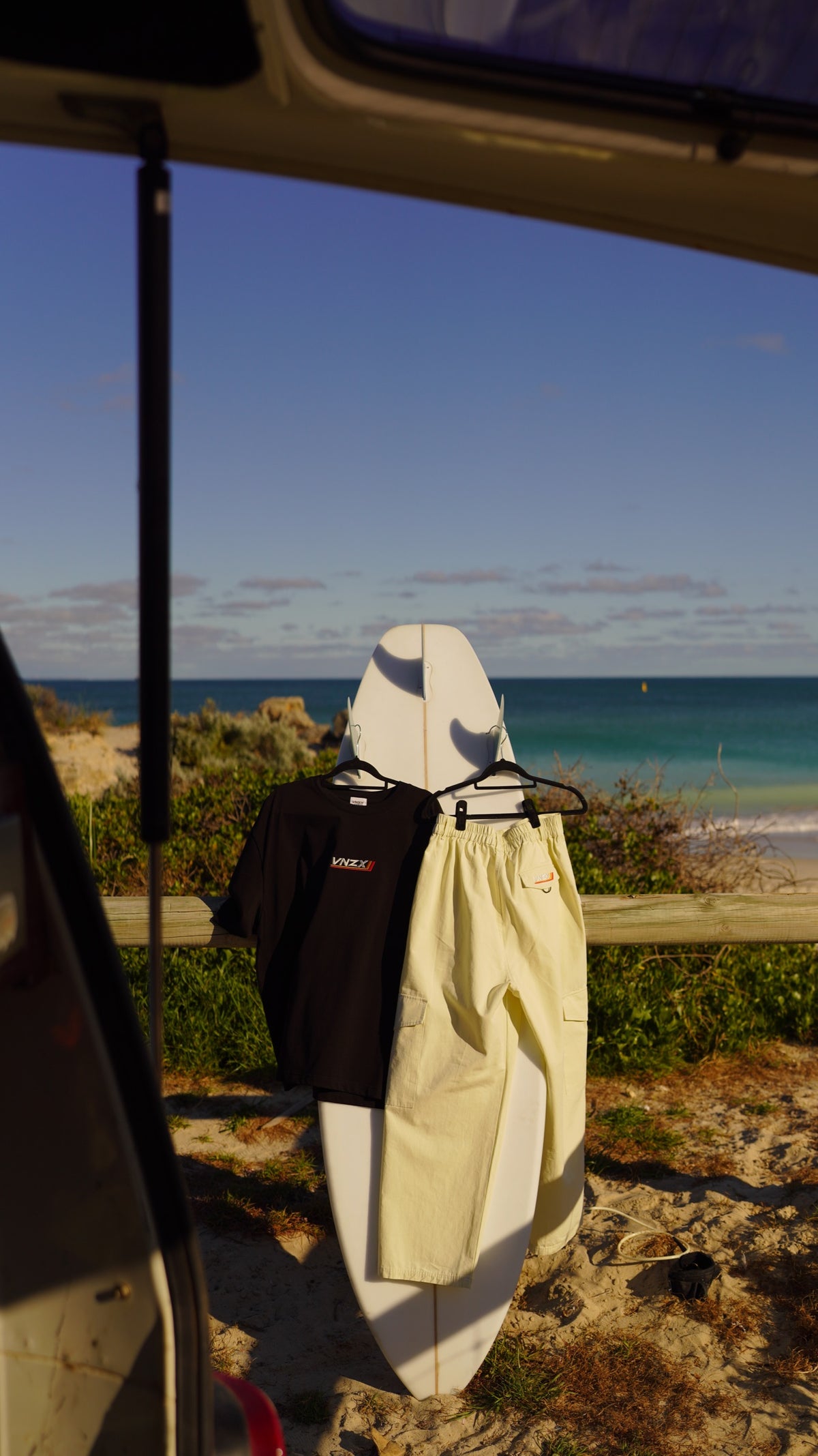 cream cargo pants hanging on a surfboard at the beach